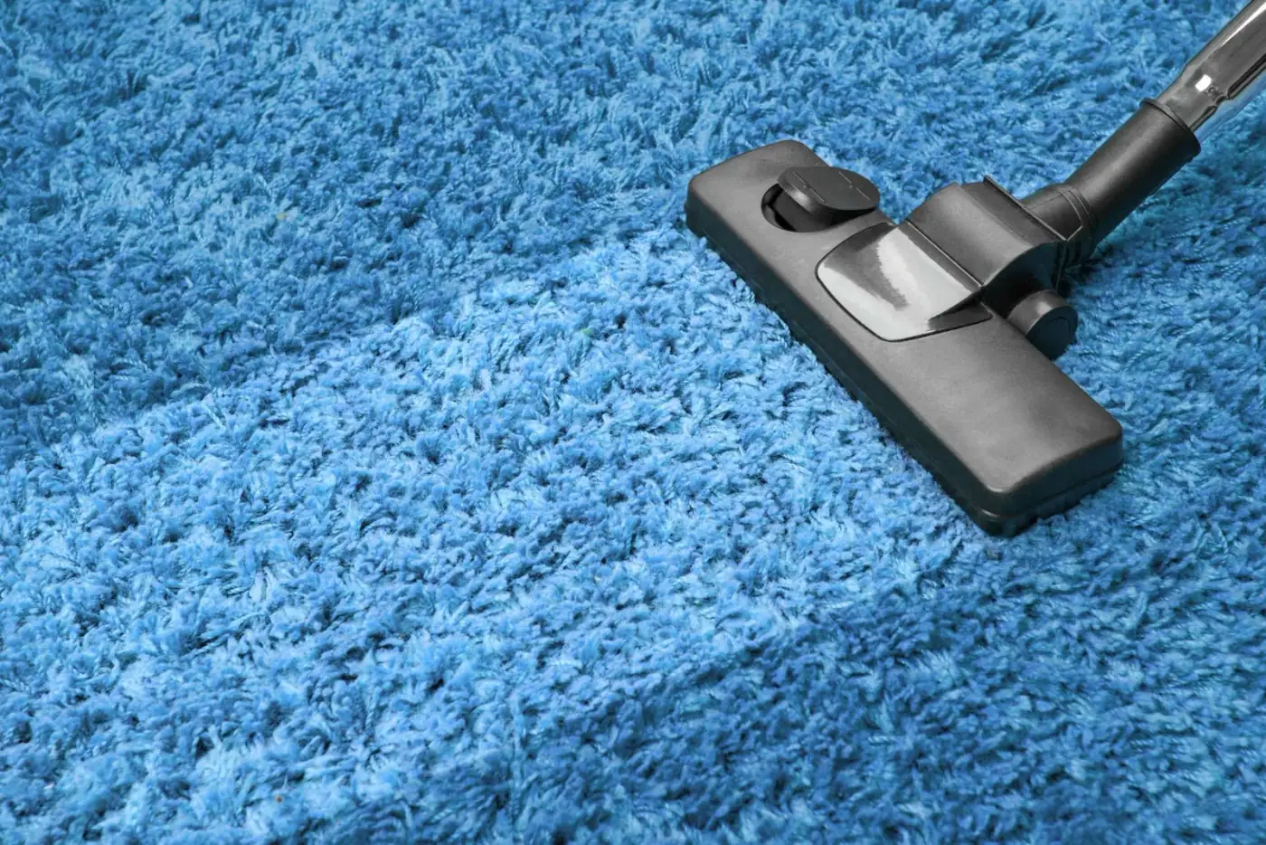 Vacuum cleaner cleaning blue carpet.
